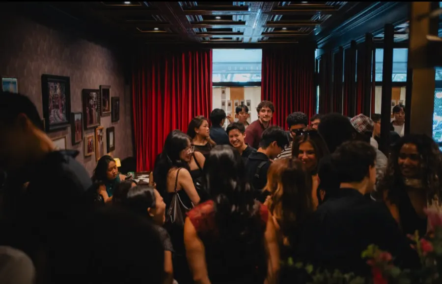 A crowd gathered in the venue under red stage curtains.