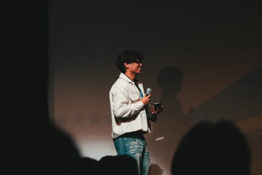 A speaker mid-talk under a single spotlight.